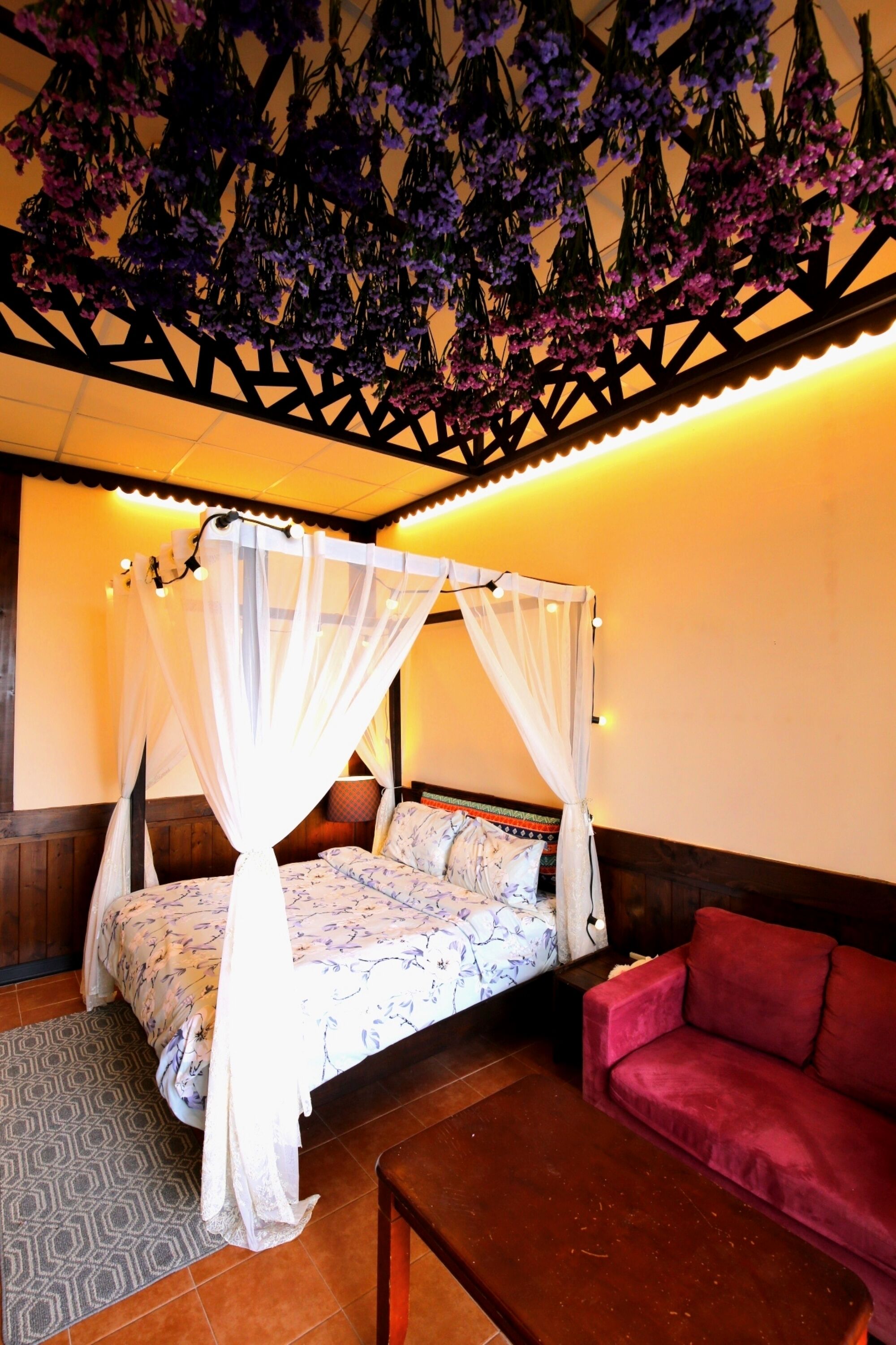 Une chambre avec un lit à baldaquin, un canapé rouge et un tapis à motifs.