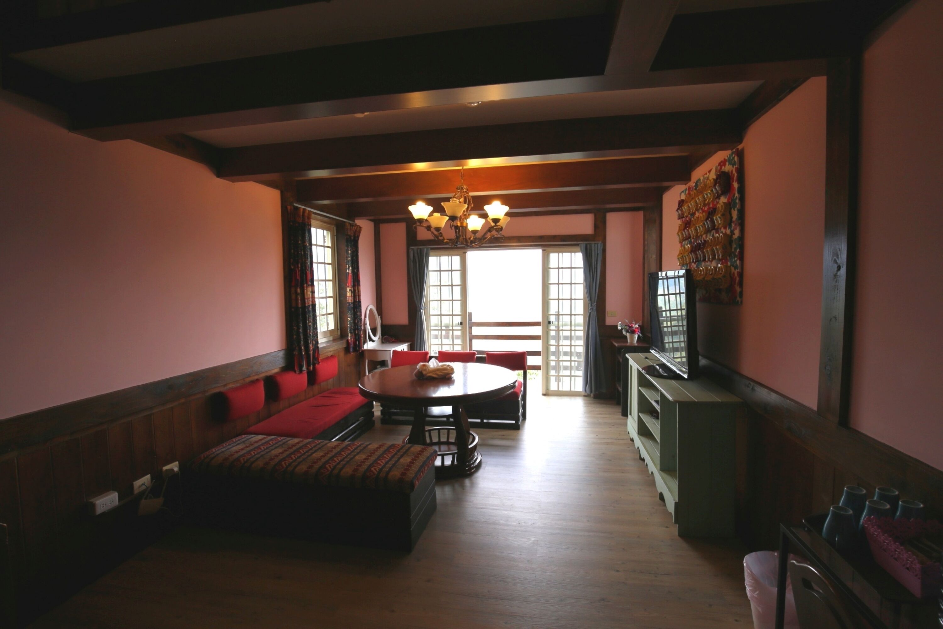 A spacious living room with a wooden floor, a round dining table, and a sofa.