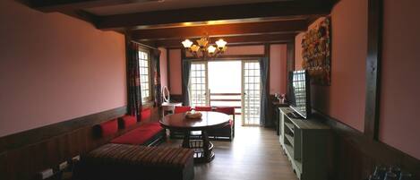 A spacious living room with a wooden floor, a round dining table, and a sofa.
