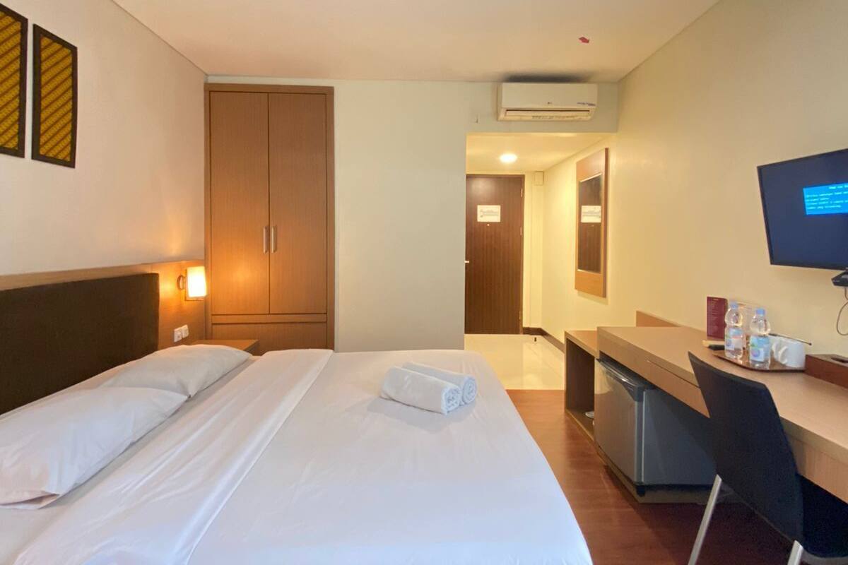 Una habitación de hotel con cama, escritorio, silla y televisión.