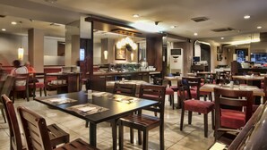 Un restaurante con varias mesas, sillas y una zona de cocina.