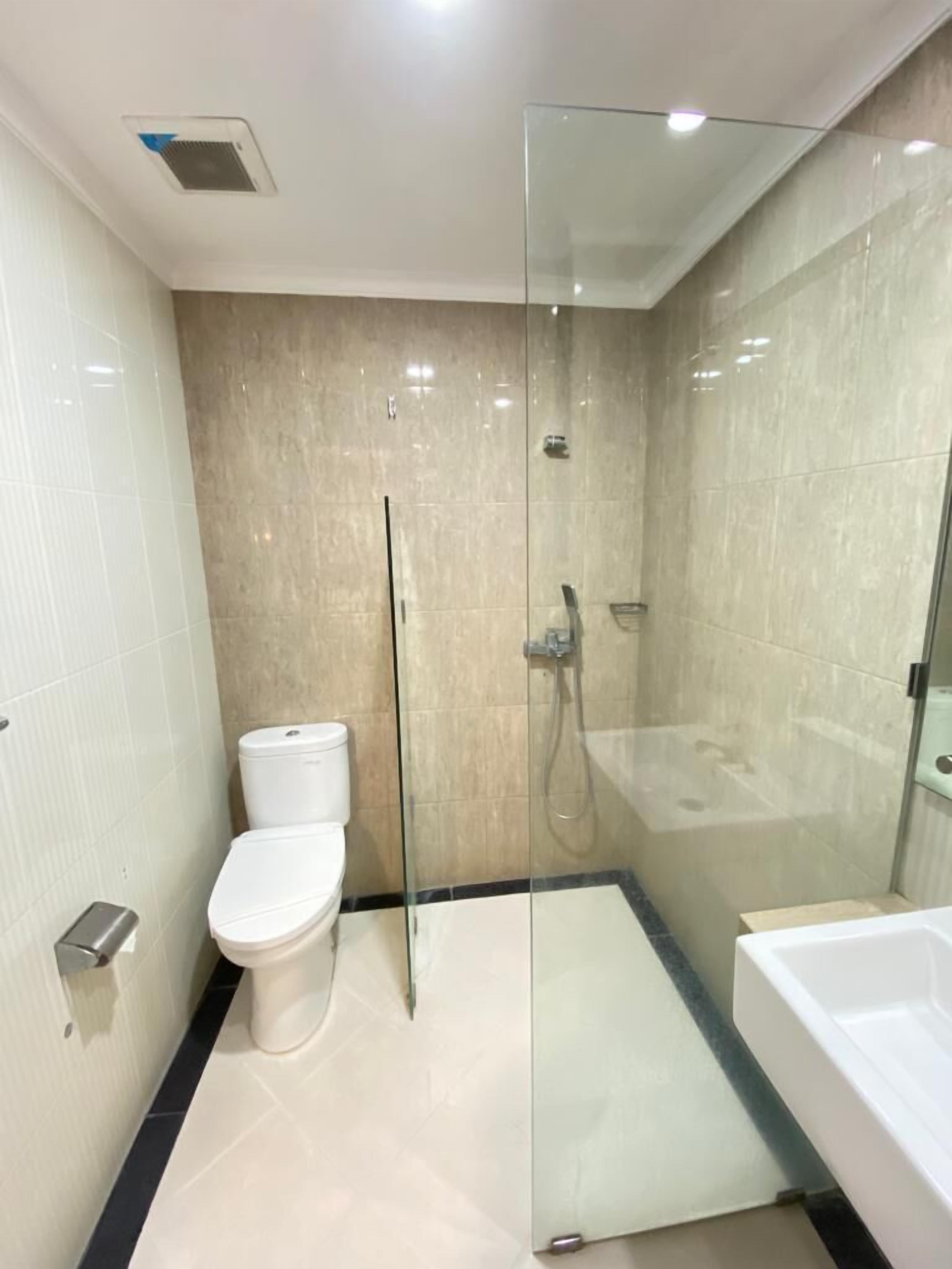 A modern bathroom with a glass-enclosed shower, a toilet, and a bathtub.
