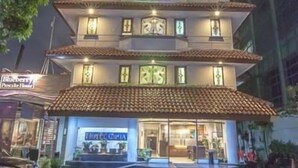 Un hotel de varios pisos con tejado de baldosas y señalización iluminada.