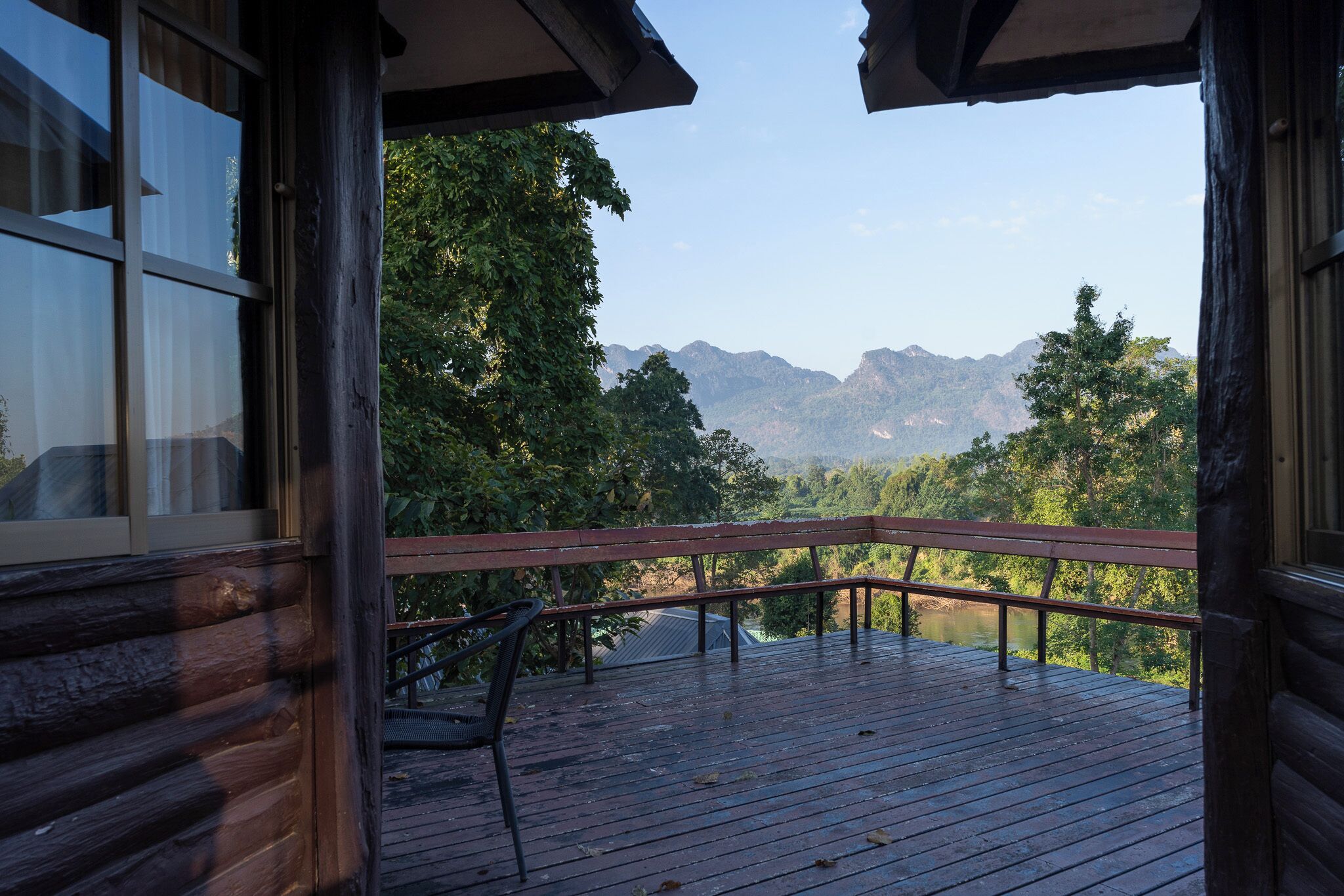 A wooden deck with a bench, overlooking a mountainous landscape.