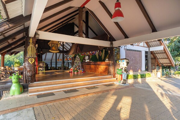 Un espacio al aire libre cubierto con un banco de madera, un pequeño árbol de Navidad y una estatua.