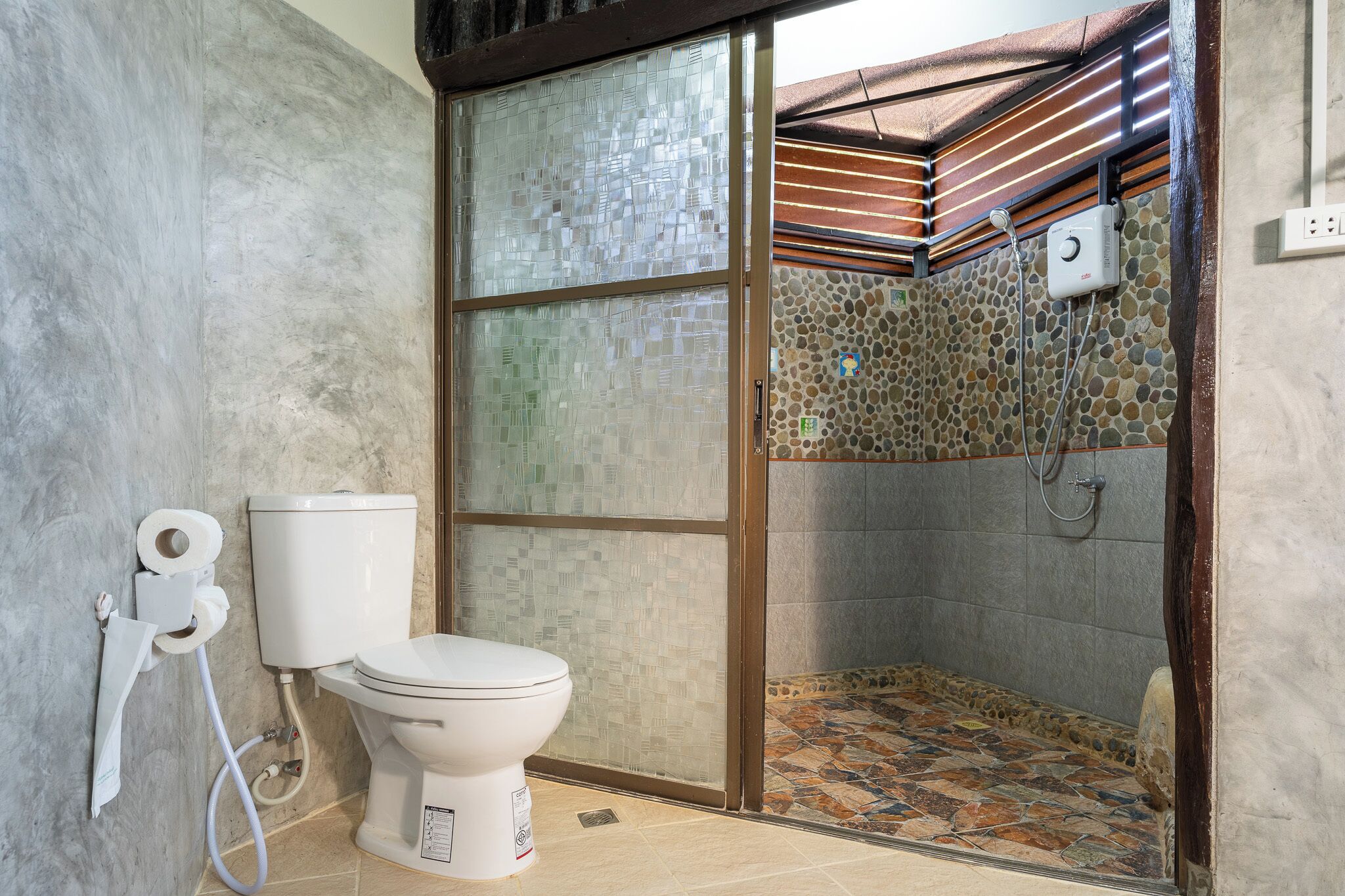 Une salle de bain équipée de toilettes, d’une douche et d’une paroi en verre.