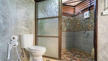 A bathroom with a toilet, a shower, and a glass partition.