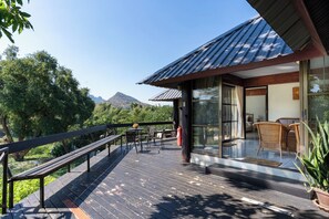 A wooden deck with outdoor furniture, a glass door entrance, and a mountain view. - Pung-waan Resort Kanchanaburi (Sai Yok)