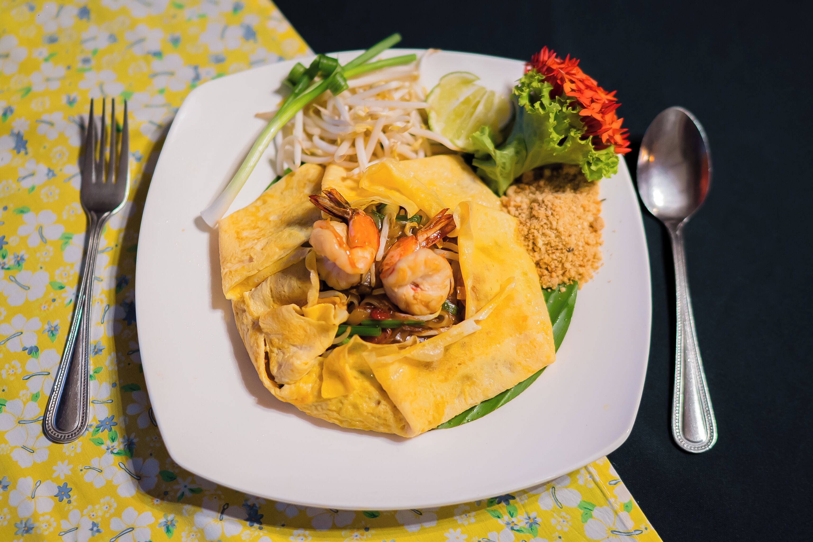 Un plato de comida con camarones, fideos y vegetales sobre un plato blanco.