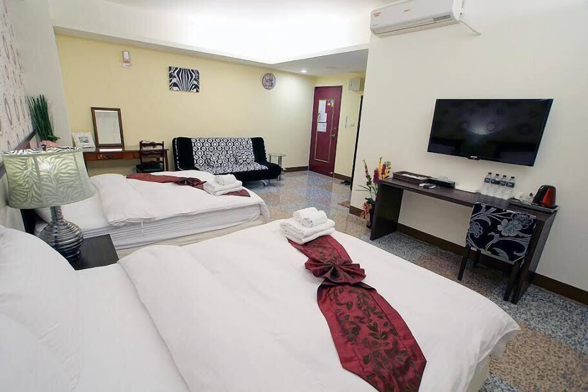 A hotel room with two beds, a TV, a desk, and a chair.