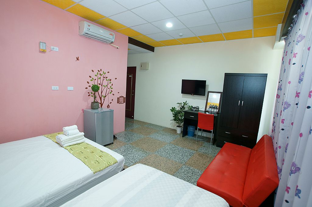 Habitación de hotel con dos camas, un escritorio, una silla, un televisor y un armario.