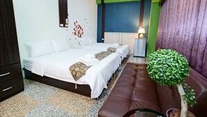Habitación de hotel con cama, un banco, una mesita, una lámpara y una planta.