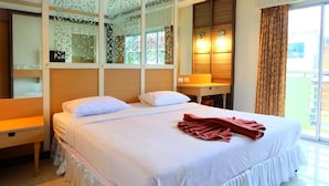 Une chambre d’hôtel avec un lit, une table de chevet, un miroir et une fenêtre avec des rideaux.