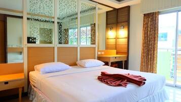 Quarto de hotel com cama, mesa de cabeceira, espelho e janela com cortinas.
