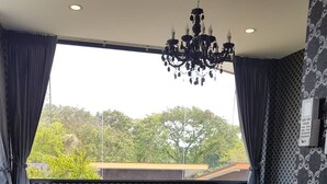 A modern bedroom with a large bed, a chandelier, and a view of greenery outside. - D-Sine Resort (Buriram)