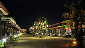 A nighttime street view with illuminated buildings and trees. - D-Sine Resort (Buriram)