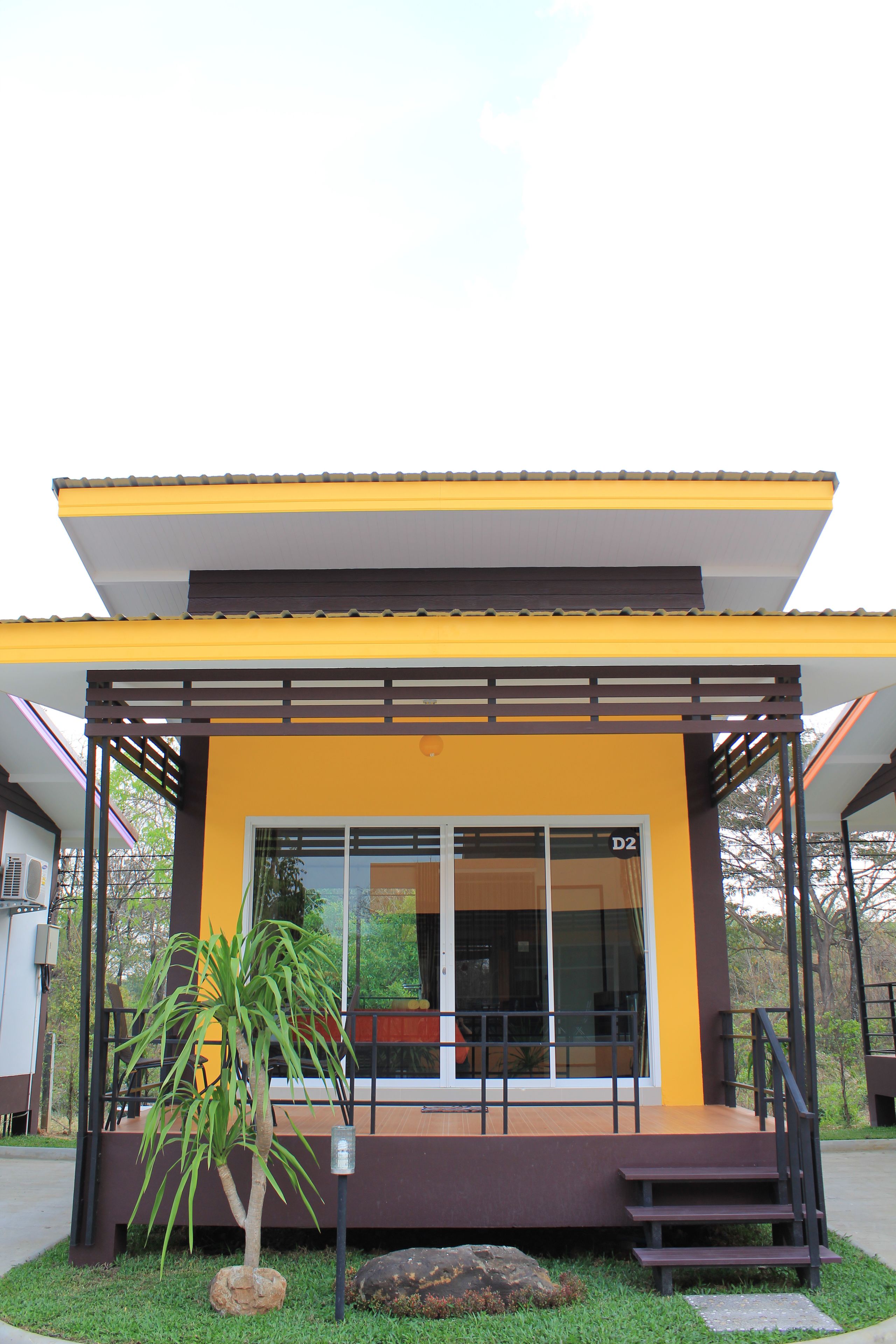 A modern building with a yellow facade, large glass windows, and a wooden deck.