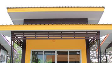 A modern building with a yellow facade, large glass windows, and a wooden deck.