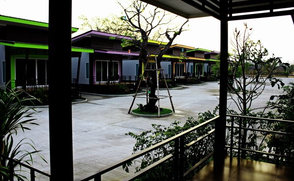 A courtyard with a central tree, surrounded by buildings with green and purple facades.