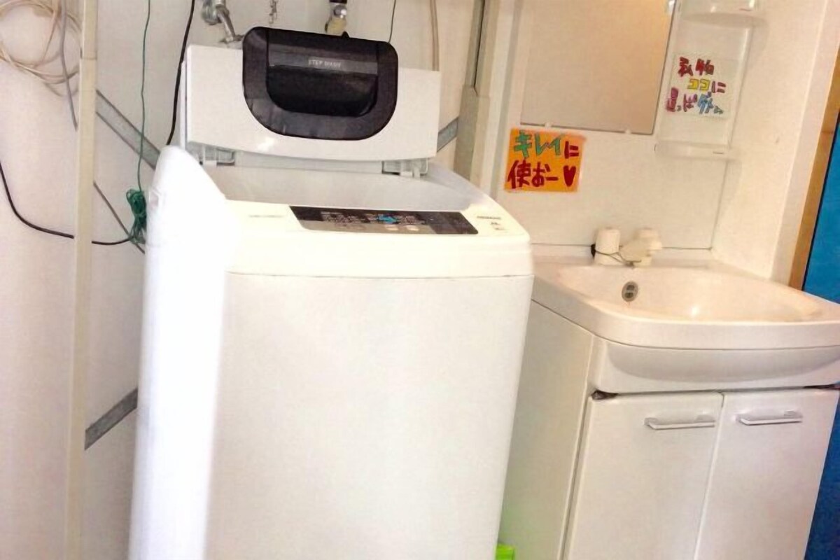 A compact room with a white washing machine, a sink, and a cabinet.