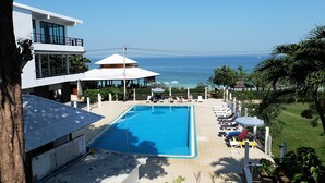 Area piscina con lettini e ombrelloni, con vista su un mare azzurro e limpido.