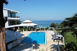 Una piscina al aire libre, sombrillas, sillones reclinables de piscina