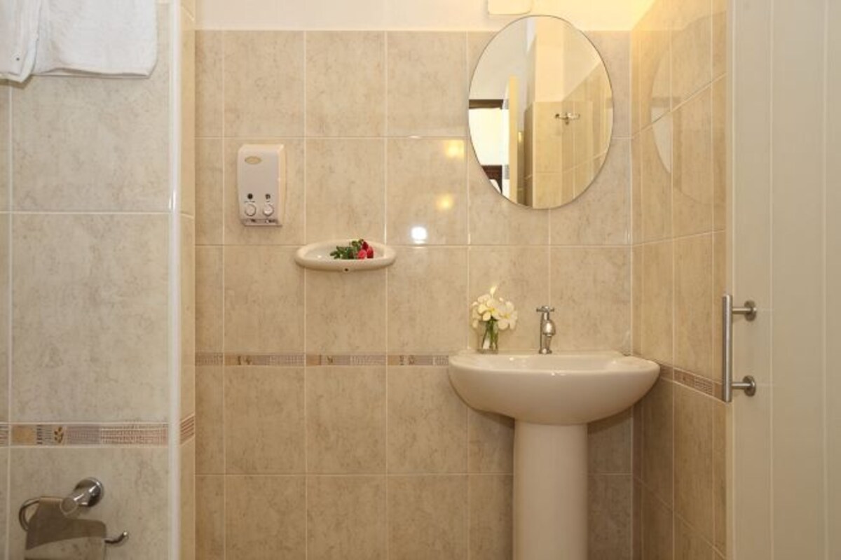 Un baño con lavamanos, espejo, dispensador de jabón y un pequeño adorno en la pared.