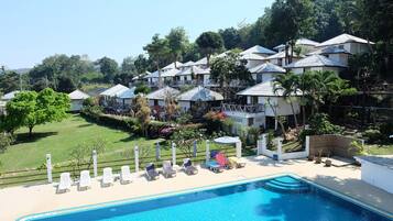 Una piscina al aire libre, sombrillas, sillones reclinables de piscina
