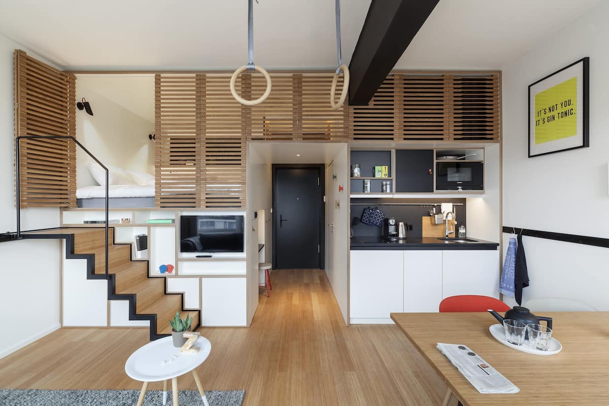 Una cocina moderna con horno empotrado, microondas y un pequeño comedor con mesa y sillas.