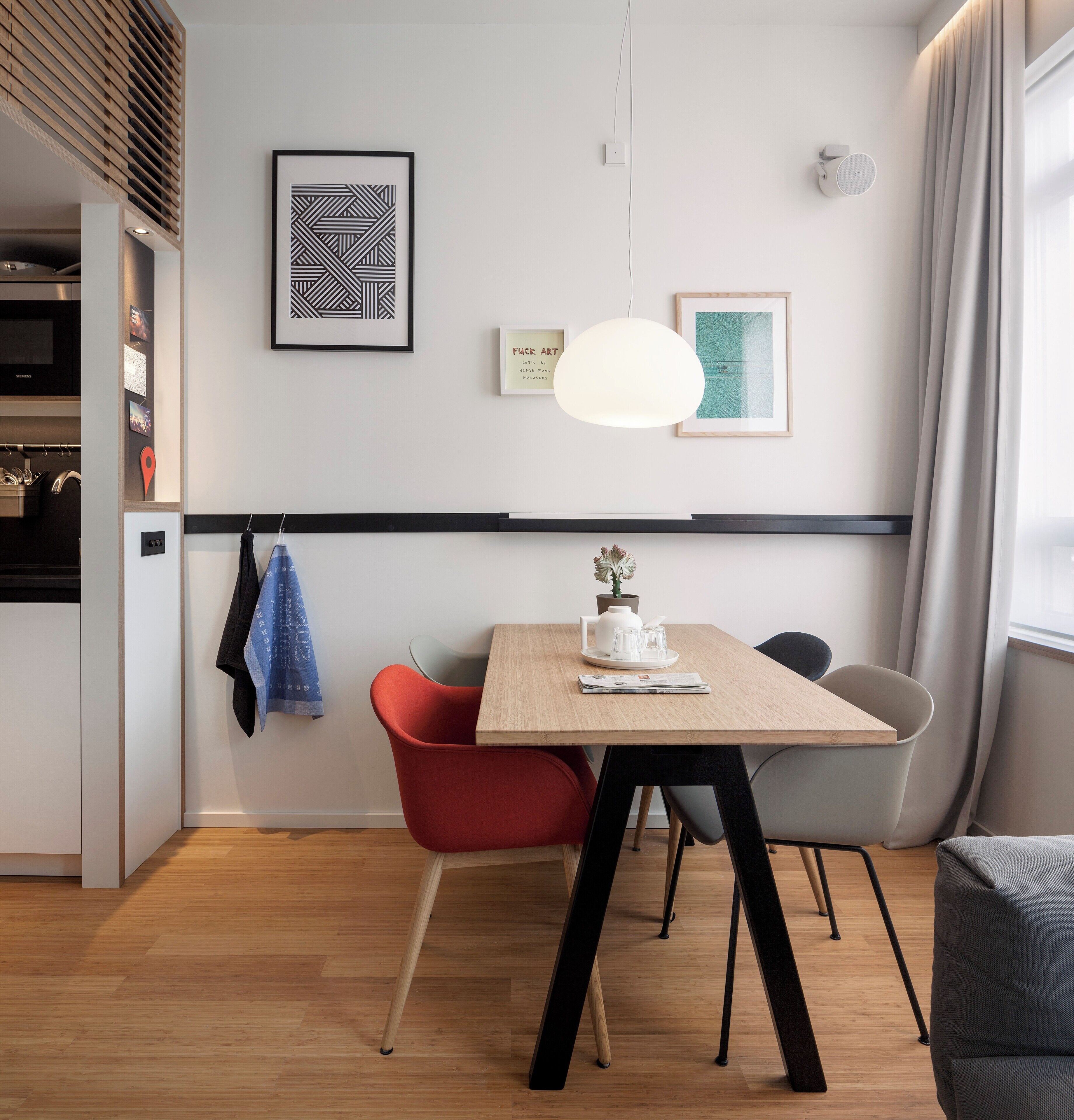 A modern dining area with a wooden table, red and gray chairs, and a pendant light.