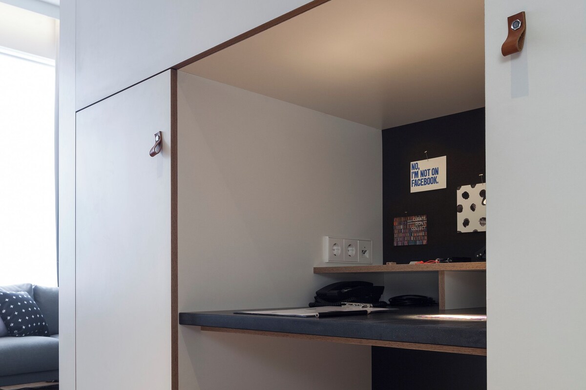 Una kitchenette pequeña con un taburete, un teléfono en la pared y un cartel que dice 'No estoy en Facebook'.