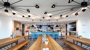 Una cocina moderna con una isla central, iluminación colgante negra y un suelo con estampado de cuadros.