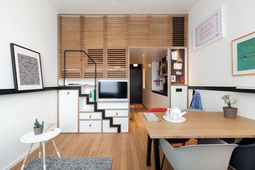 Un espacio habitable funcional con televisor, kitchenette y comedor.