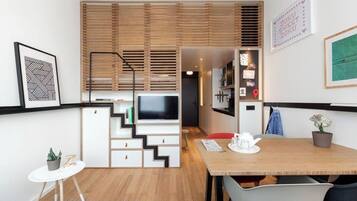 Un espacio habitable funcional con televisor, kitchenette y comedor.