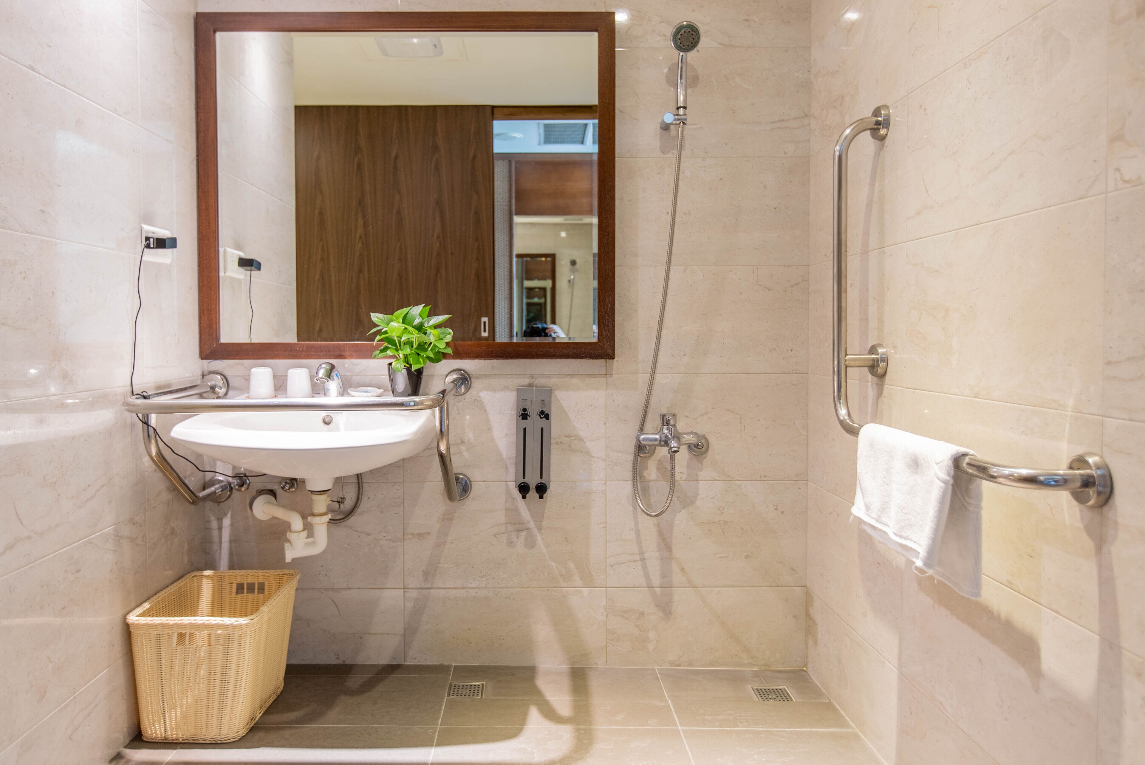 Un baño moderno con lavamanos, espejo, ducha y perchero.