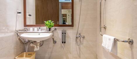 Un baño moderno con lavamanos, espejo, ducha y perchero.