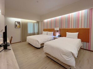 Ein Hotelzimmer mit zwei Betten, einem Schreibtisch mit Computer, einer Lampe und einer gestreiften Wand.