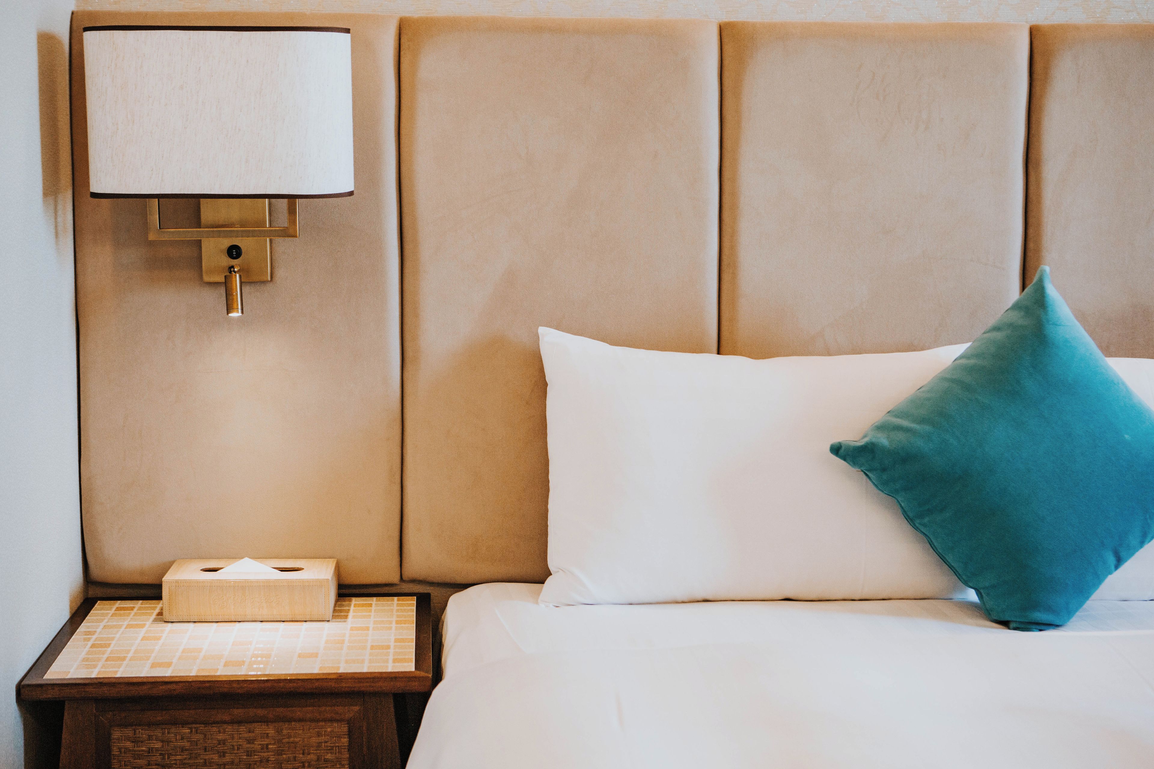 A hotel room with a bed, a nightstand, a lamp, and a tissue box.