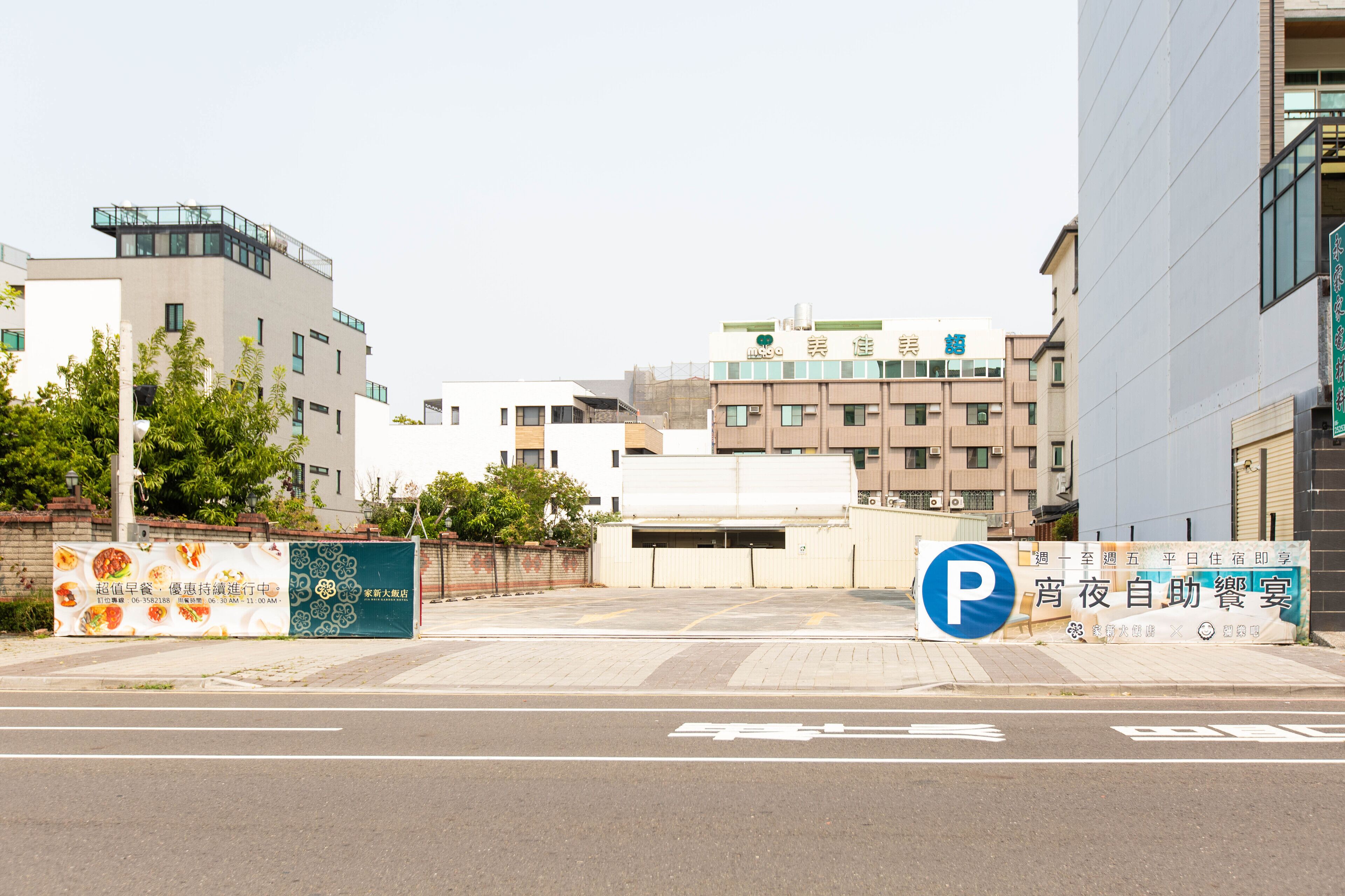 A parking area with a blue 'P' sign, surrounded by buildings with signage in a foreign language.