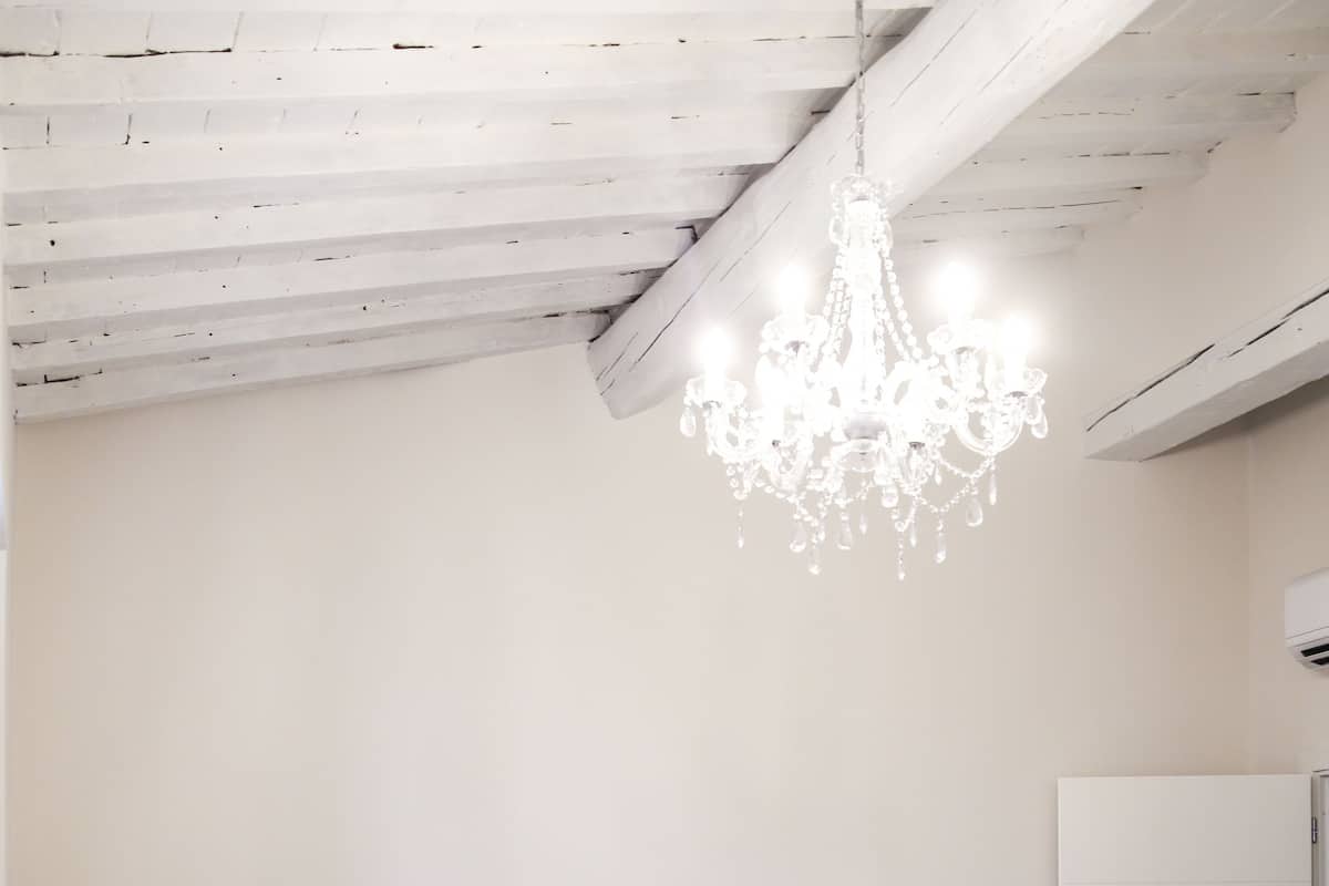 A bedroom with a large bed, bedside tables, a chandelier, and a door.