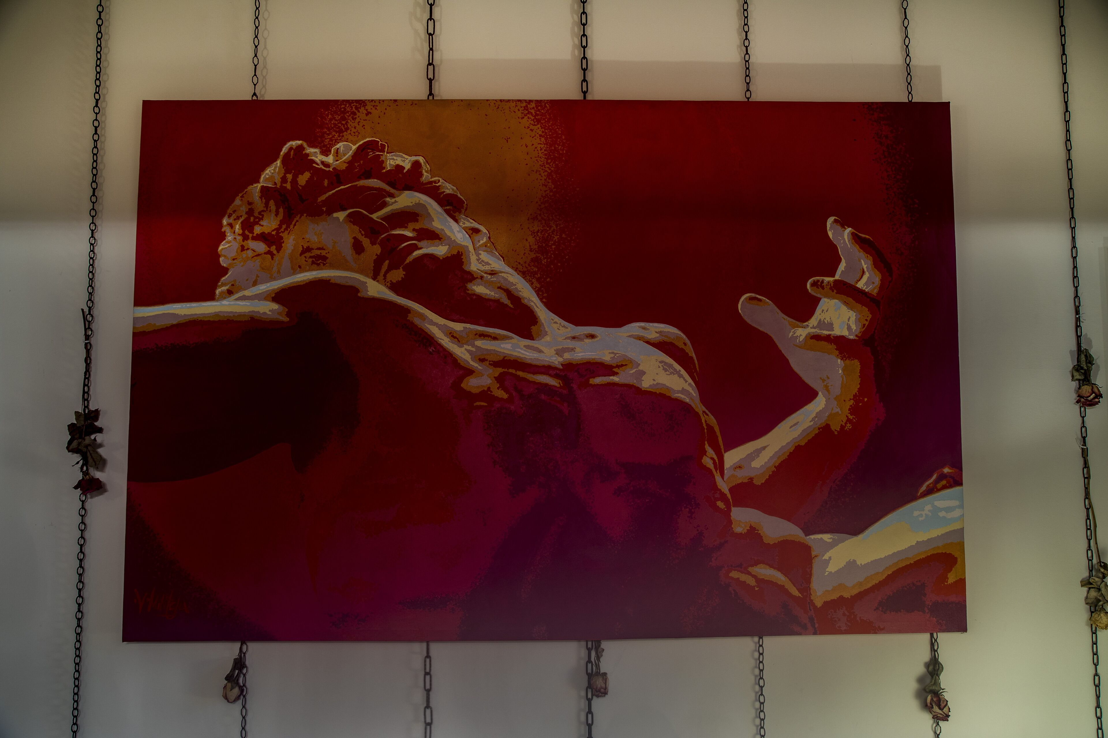A painting of a muscular figure in a dynamic pose, suspended from the ceiling by chains.