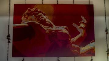 A painting of a muscular figure in a dynamic pose, suspended from the ceiling by chains.