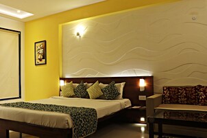 Habitación de hotel con cama, mesitas de noche, una silla y un detalle decorativo en la pared.