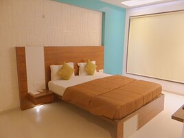 Una camera da letto moderna con una testiera in legno, un'ampia finestra e un letto rifatto con cuscini.