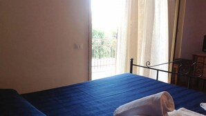 A room with a bed, a window with curtains, and a view of greenery outside. - B&B Il Cavaliere (Trapani)
