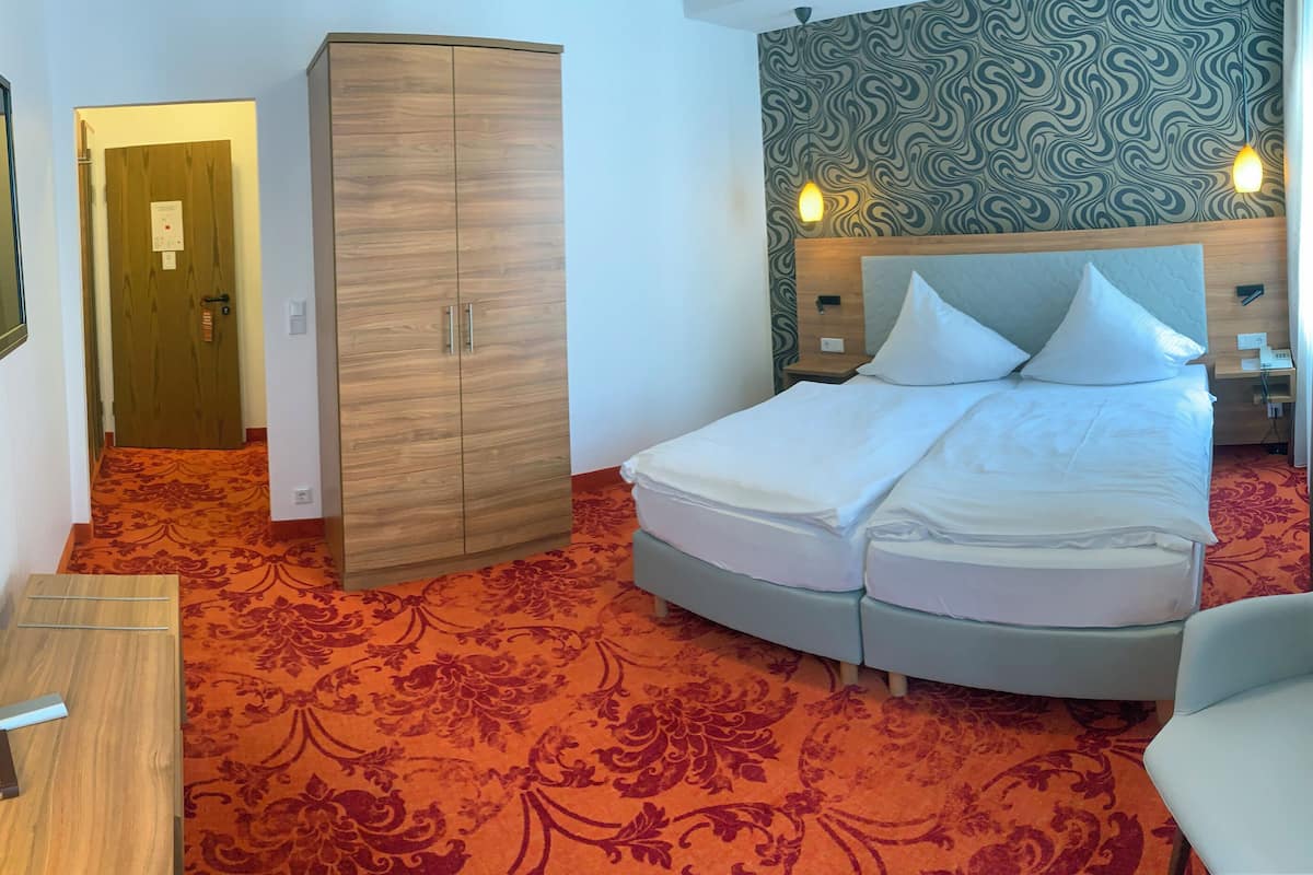 Une chambre d’hôtel avec un lit, une armoire et un téléviseur.