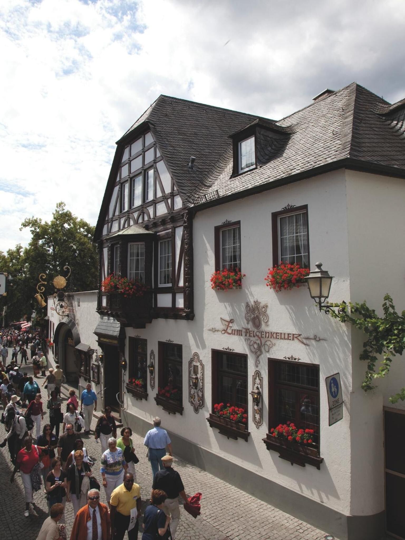 A traditional half-timbered building with a sign reading "Zum Felseckeller" and flower boxes on the windows.
