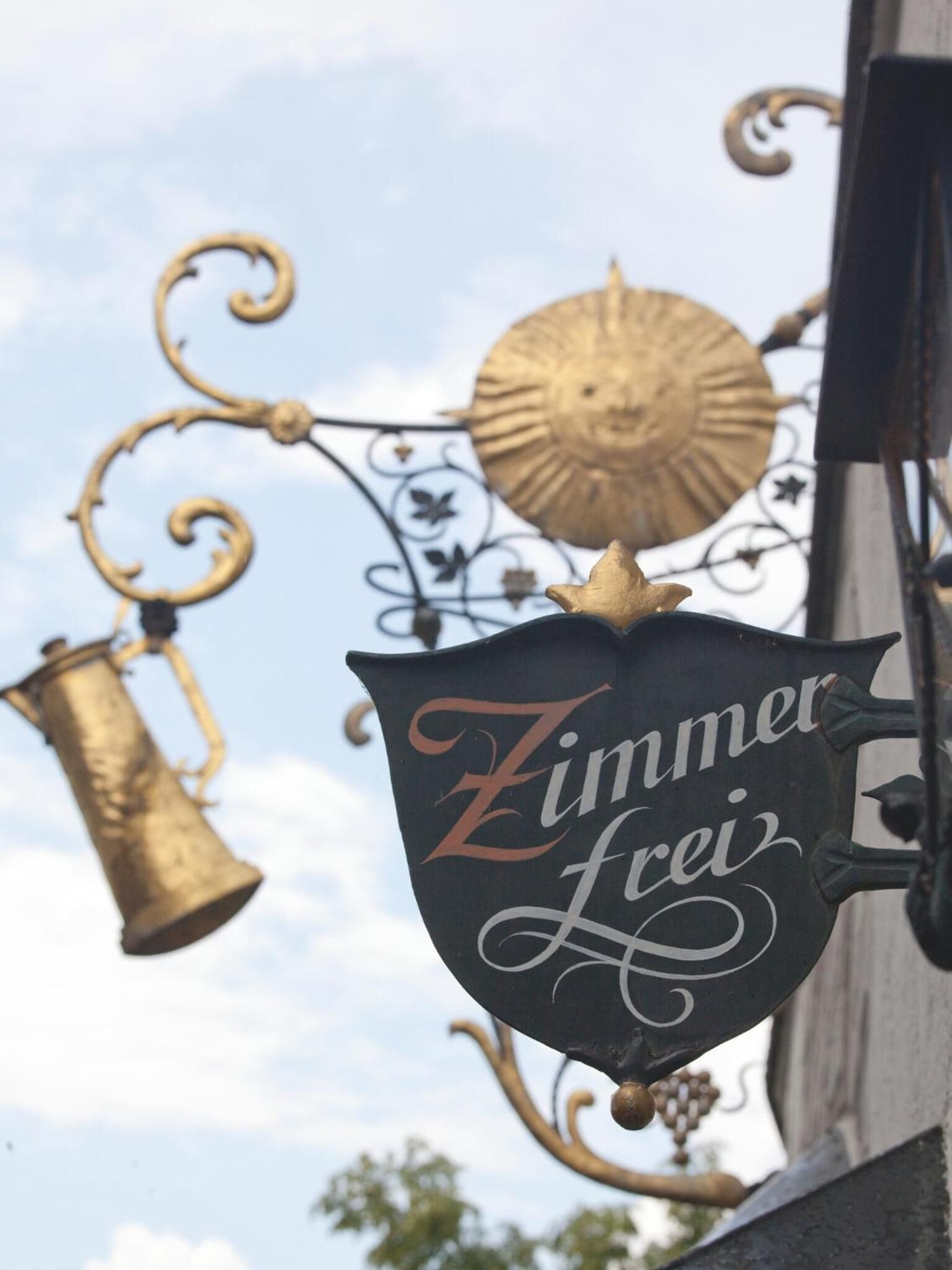 A sign with the text "Zimmer Frei" hanging from a decorative metal structure.