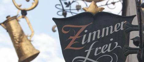 A sign with the text "Zimmer Frei" hanging from a decorative metal structure.