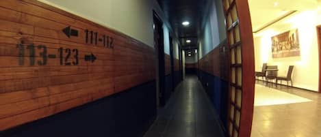 Un pasillo con señales de orientación que indican los números de habitación 113-123 y 111-112.